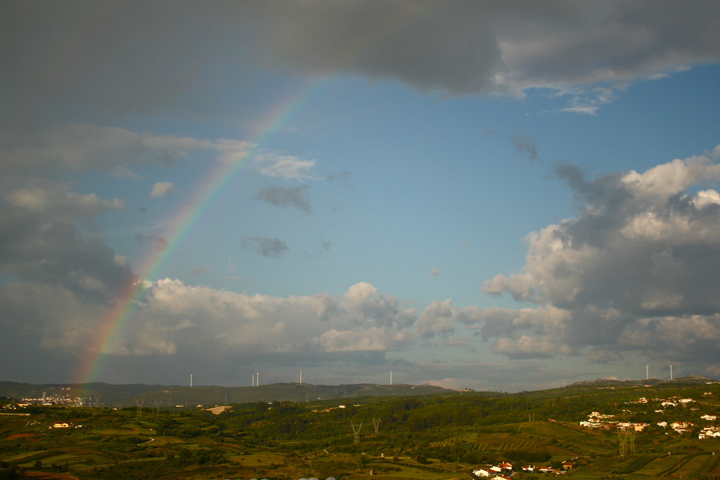 Arcobaleno che si proietta da nuvola su paesino