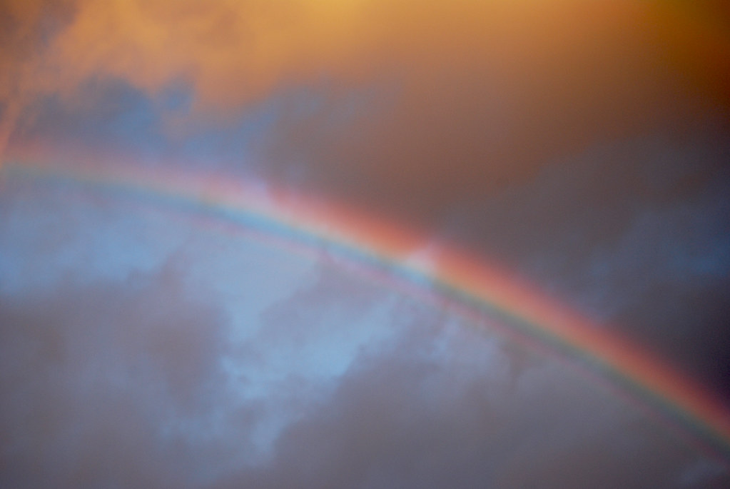 Arcobaleno con colori spenti sovrastato da nuvola arancione