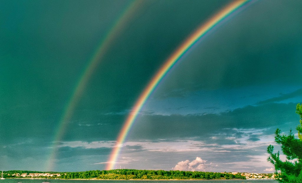 Arcobaleno con doppio in cielo verde su prato verde