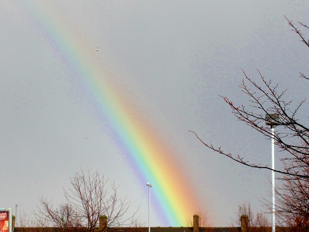 Arcobaleno di grande spessore che sale verso il cielo