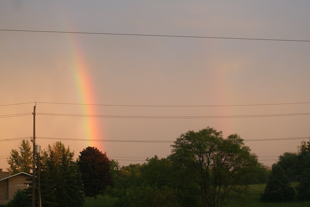 Arcobaleno dietro tralicci della corrente