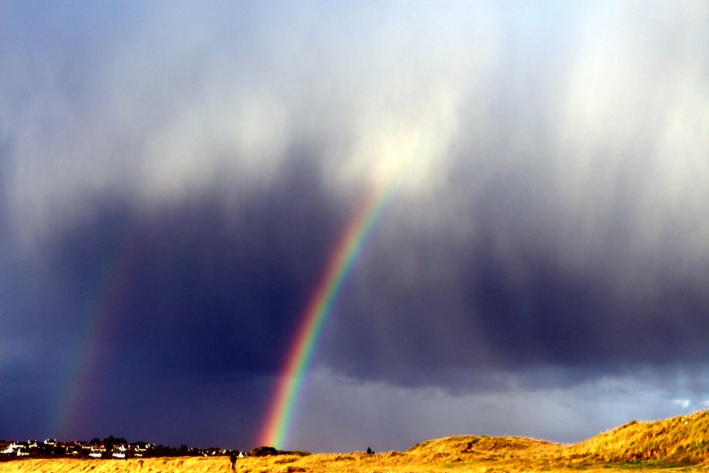 Arcobaleno doppio che fuoriesce da nuvole molto minacciose