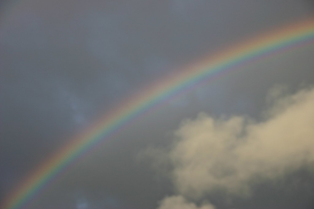 Arcobaleno in diagonale con accanto una nuvola