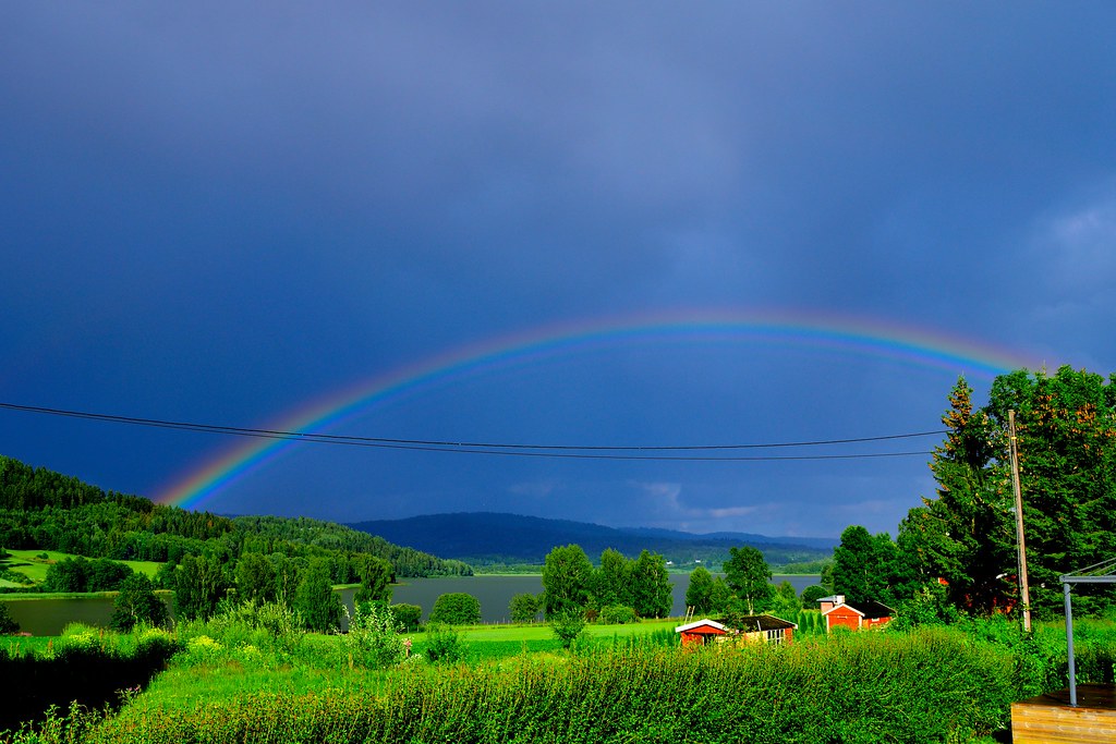 Arcobaleno in un bel cielo blu sopra un bel prato verde