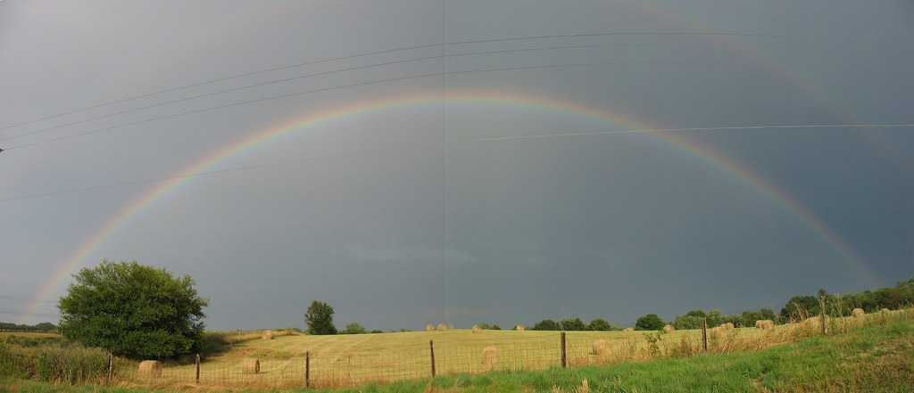 Arcobaleno intero sopra prato multicolore