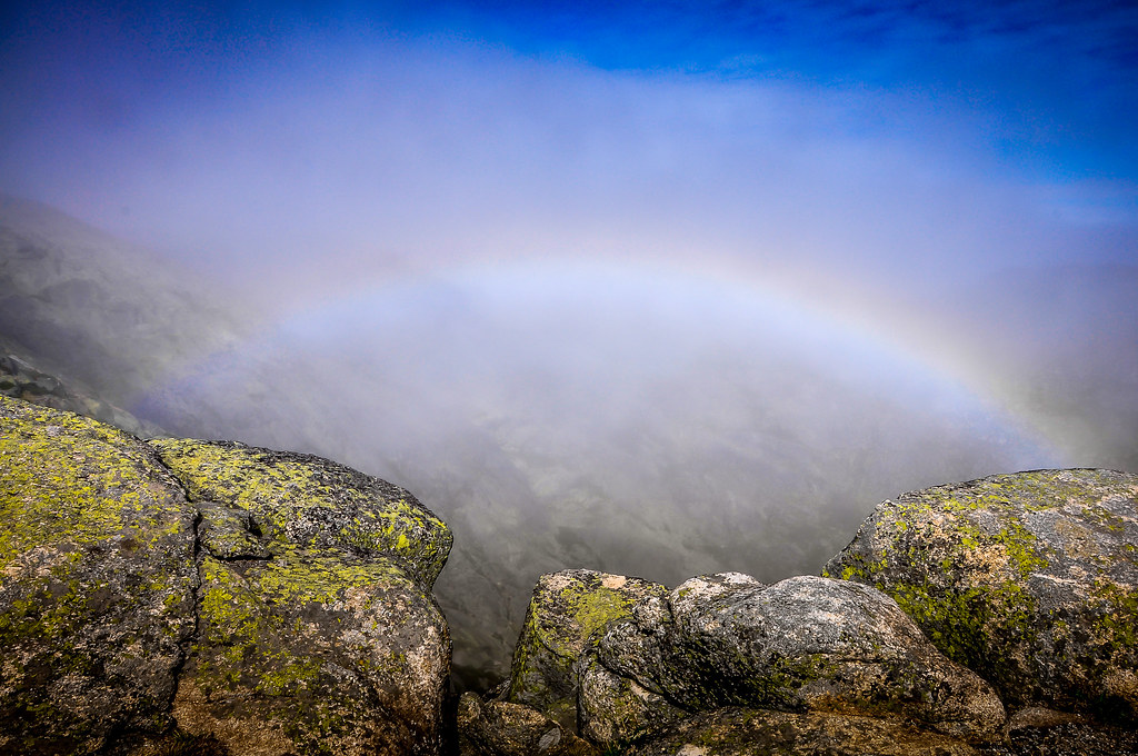 Arcobaleno nella nebbia oltre le rocce