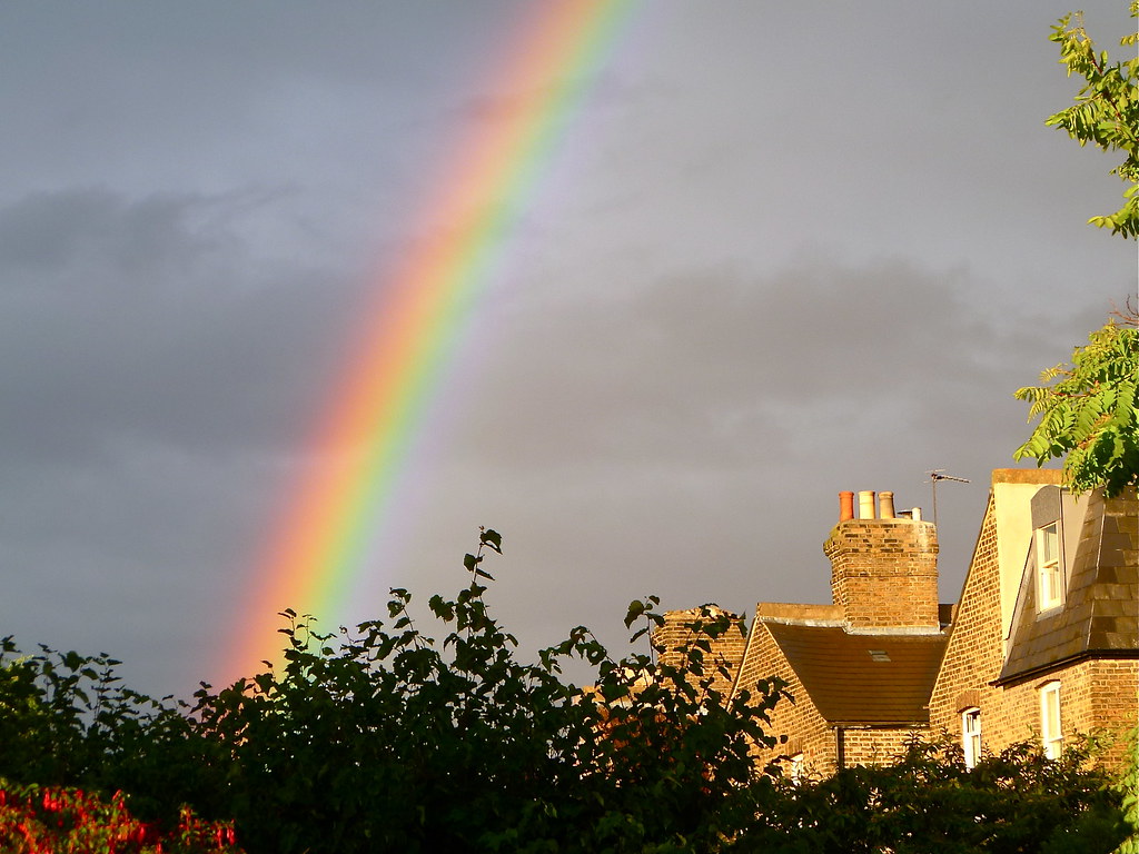 Arcobaleno quasi verticale sopra varie case