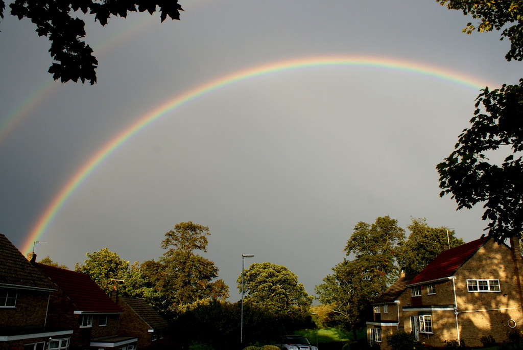 Arcobaleno sopra alberi e case