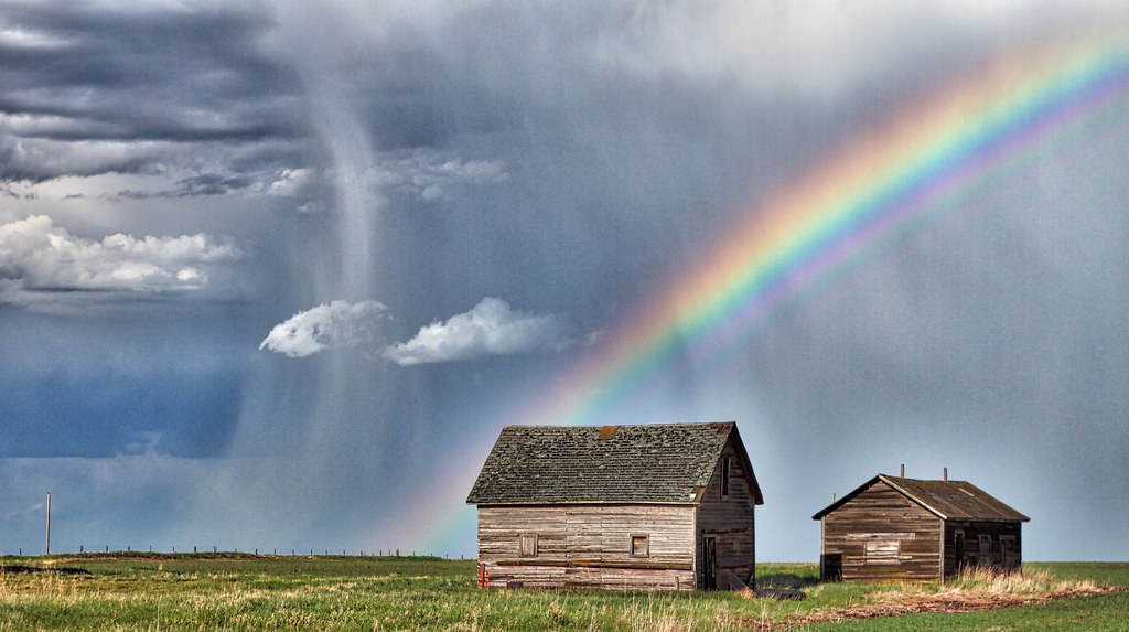 Arcobaleno sopra casotte nel verde