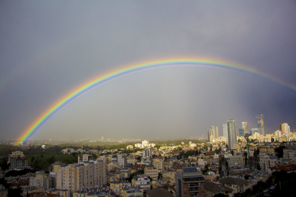 Arcobaleno sopra città con palazzi e grattacieli