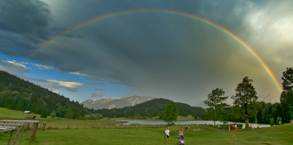 Arcobaleno sopra prato tra montagne verdi