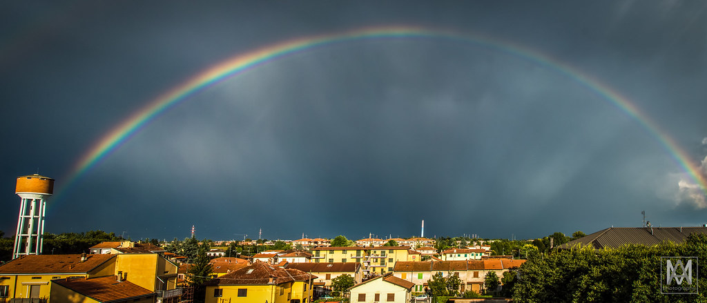 Arcobaleno storto con raggi di luce mistici che lo attraversano