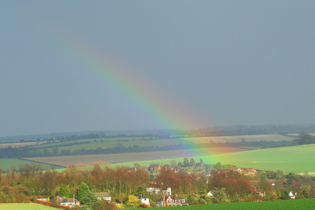 Arcobaleno tenue sopra piccola cittadina immersa nel verde