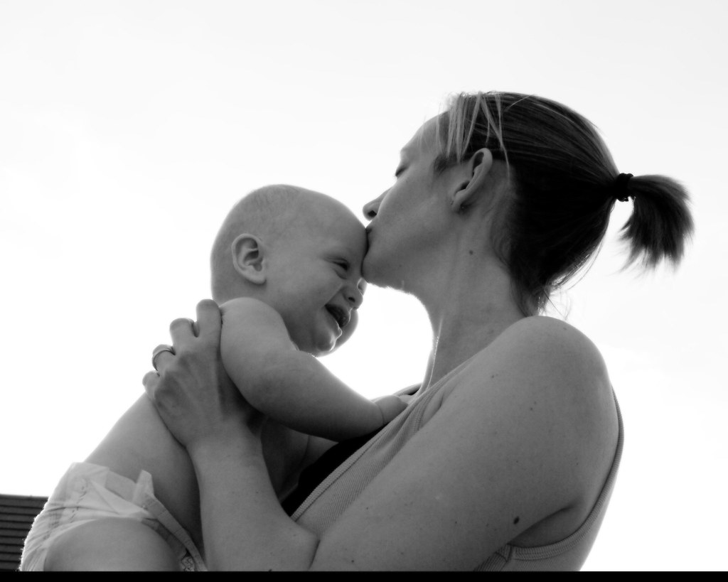 Bacio tenero di madre a figlio molto piccolo in braccio