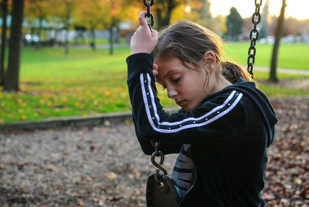 Bambina affranta in solitudine su altalena