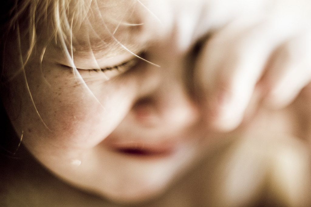 Bambino triste che piange e si tocca il viso