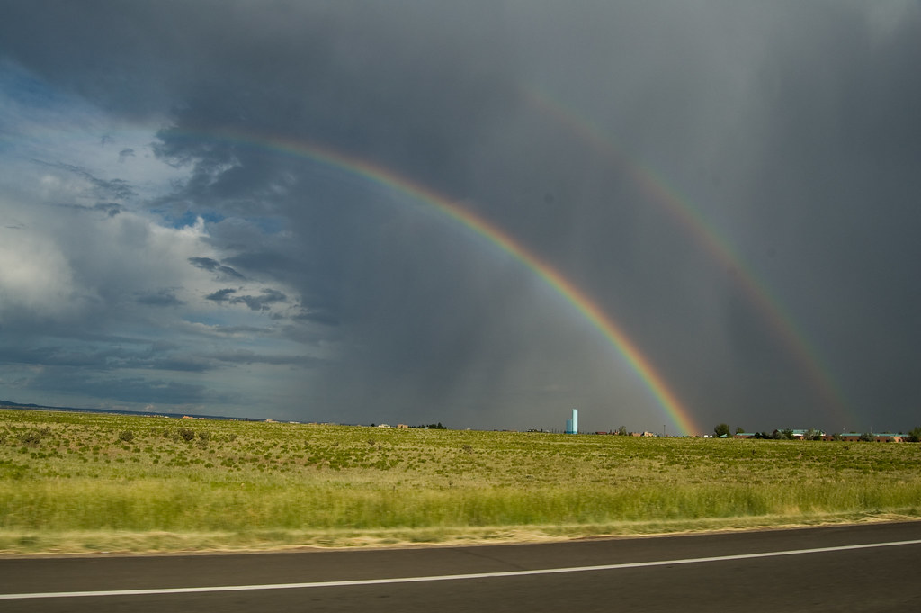 Doppio arcobaleno che sparisce in un cielo molto nuvoloso