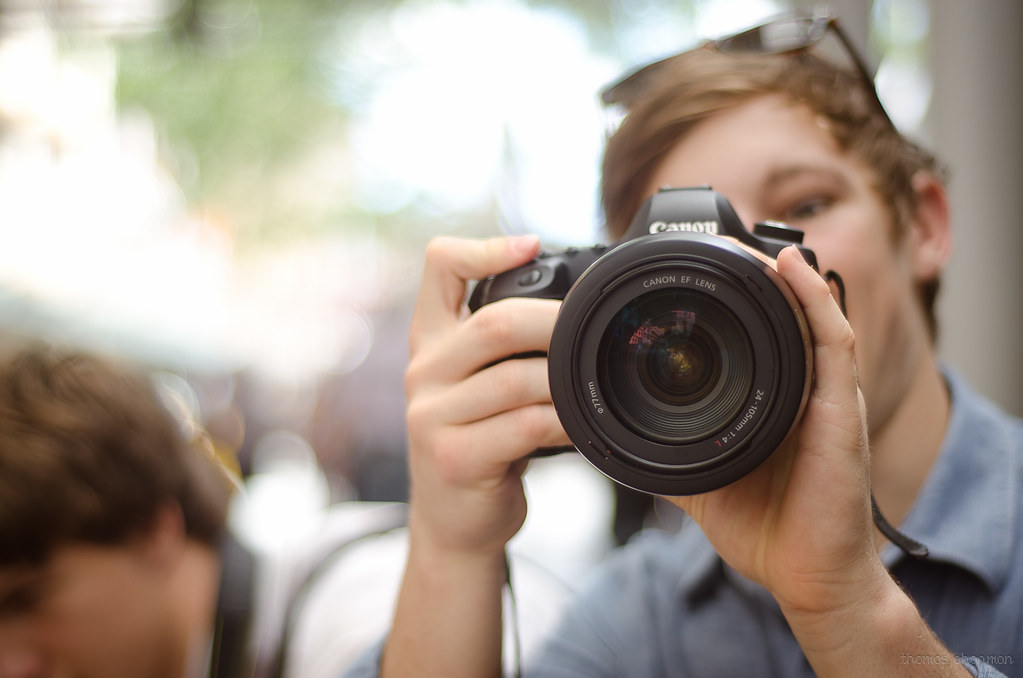 Fotografo con bella fotocamera che regola obiettivo di macchina fotografica