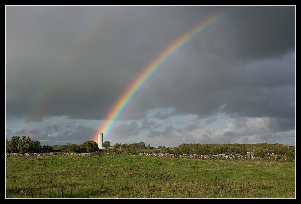 Pezzo di arcobaleno che si erge da erba verso cielo