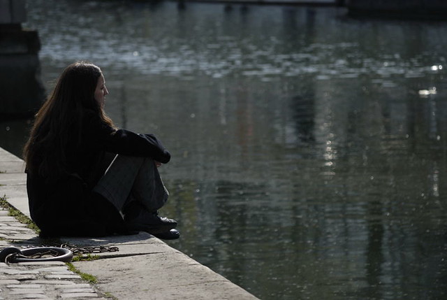 Ragazza malinconica rannicchiata sulla riva della Senna a Parigi