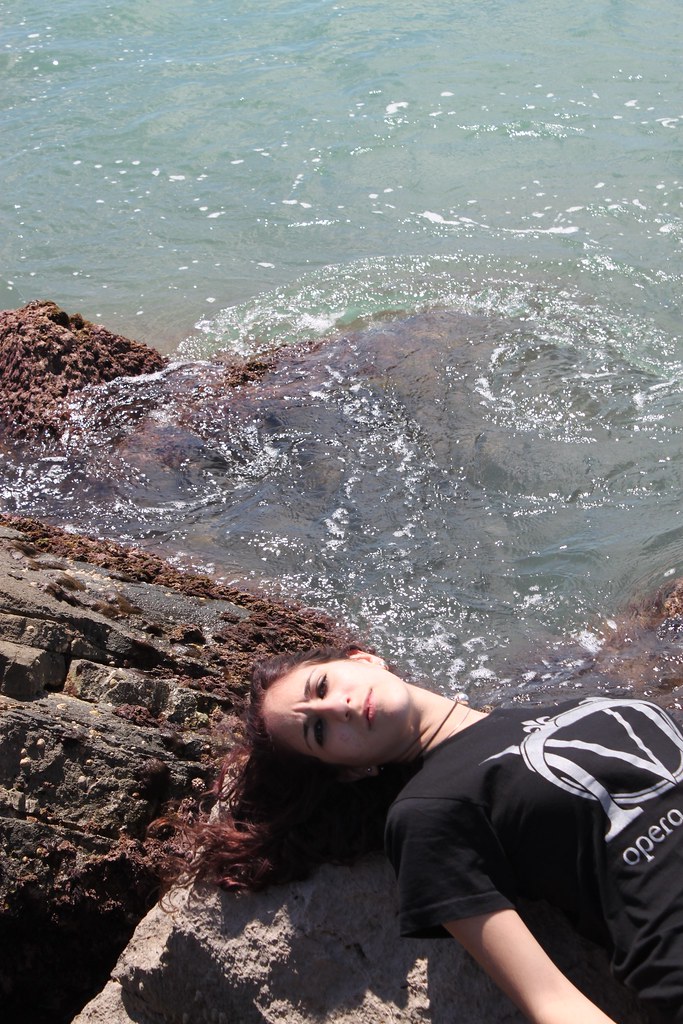 Ragazza triste sdraiata su un masso al mare in Spagna