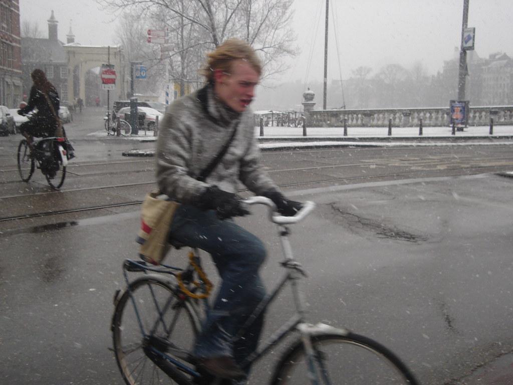 Ragazzo affannato in bicicletta in una giornata piovosa ad Amsterdam