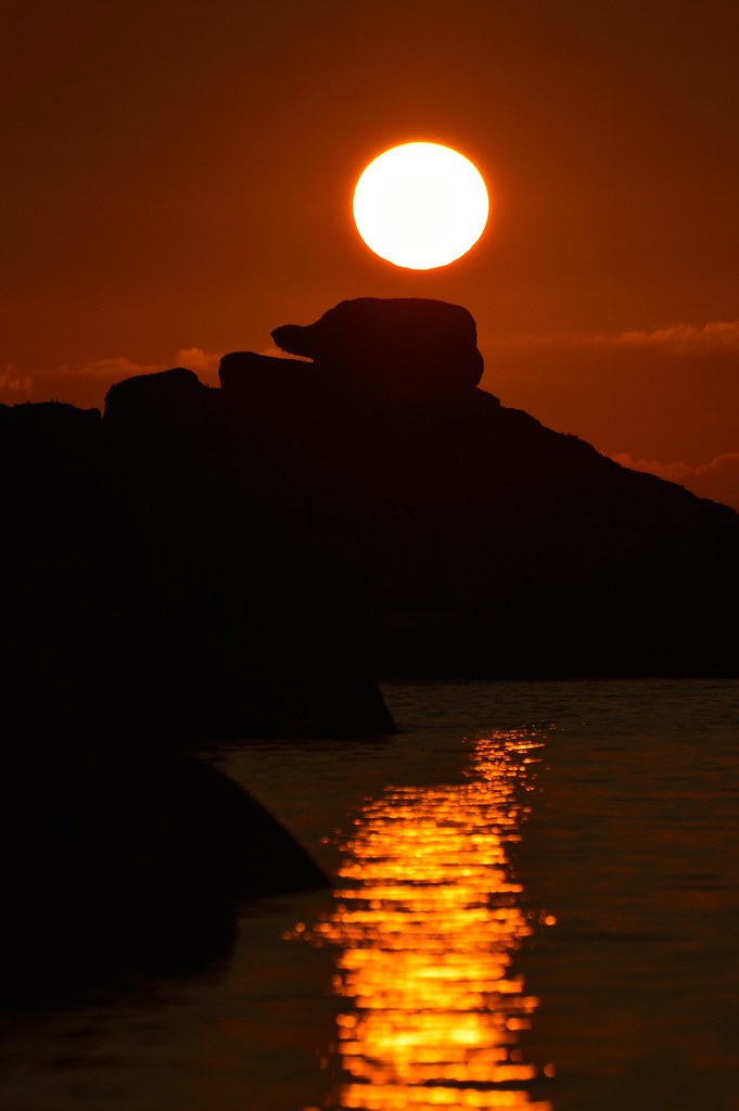 Sole bello come luna mentre tramonta su promontorio