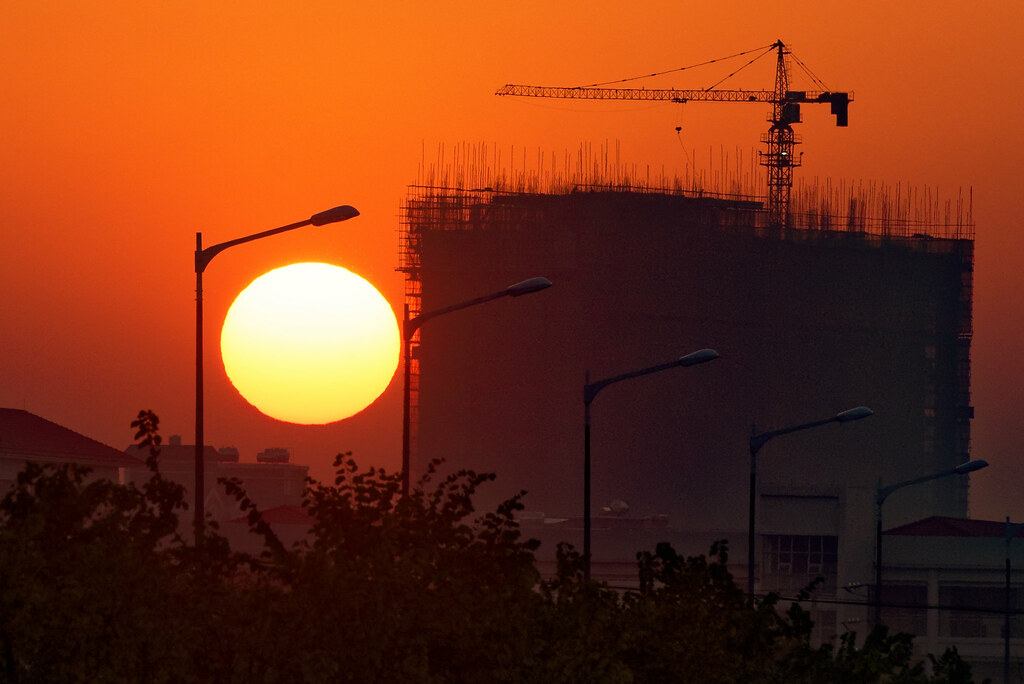 Tramonto con sole gigante e fabbrica in costruzione