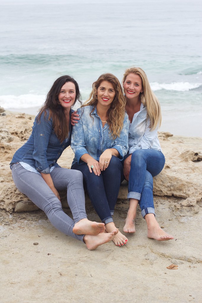 Tre belle ragazze sedute sulla spiaggia che sorridono