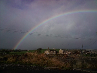 Arcobaleno in paesaggio drammatico sul mare