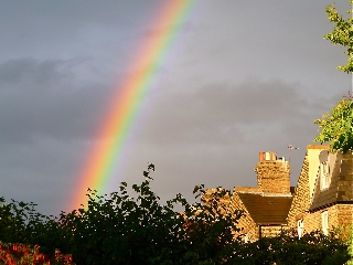 Arcobaleno quasi verticale sopra varie case