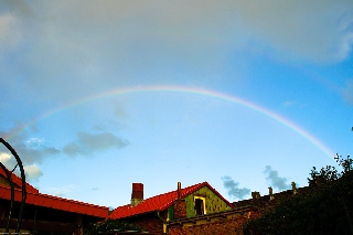 Arcobaleno sottile sopra bella casa rossa