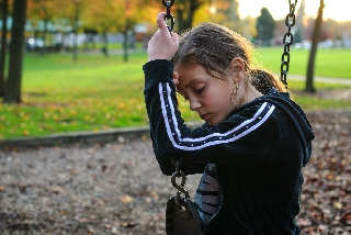 Bambina affranta in solitudine su altalena