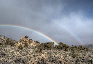 Doppio arcobaleno sopra terreno roccioso